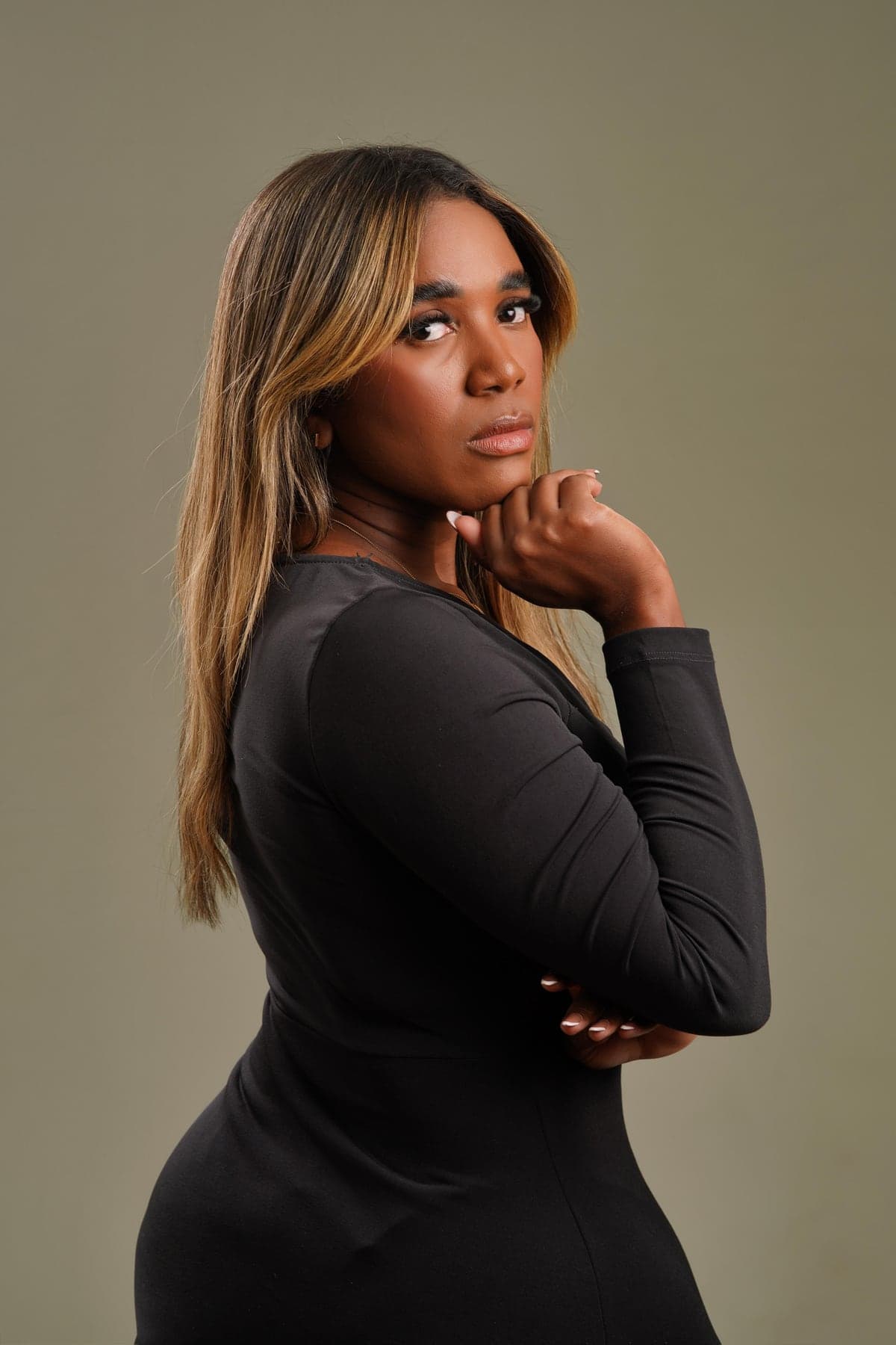 Rafaela Santos, lash designer, de vestido preto, olhando por cima do ombro